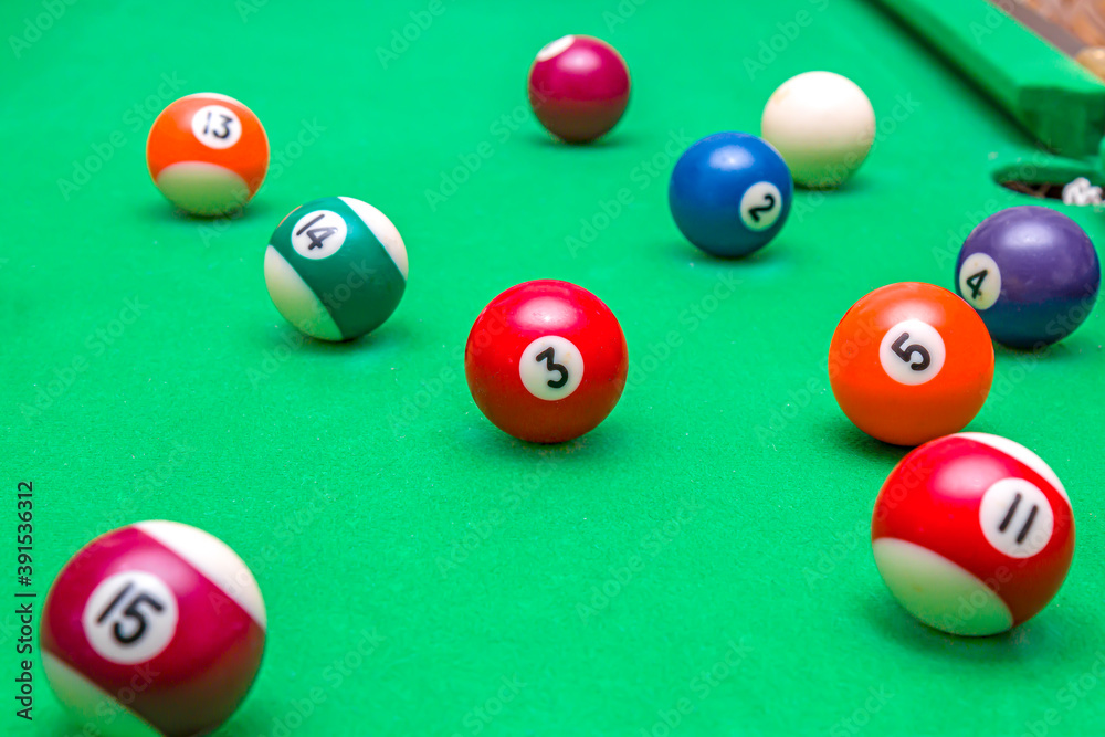 Sports game of billiards on a green cloth. Multi-colored billiard balls with numbers on a pool table. Active leisure and entertainment. Billiards. Billiard balls close-up. Sports game of billiards on a green cloth. Multi-colored billiard balls with numbers on a pool table. Active leisure and entertainment. Billiards. Billiard balls close-up.