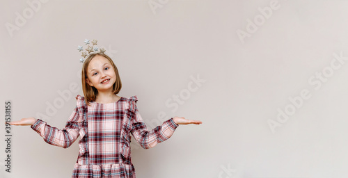 10-year-old girl on a beige background smiling, hands to the sides.