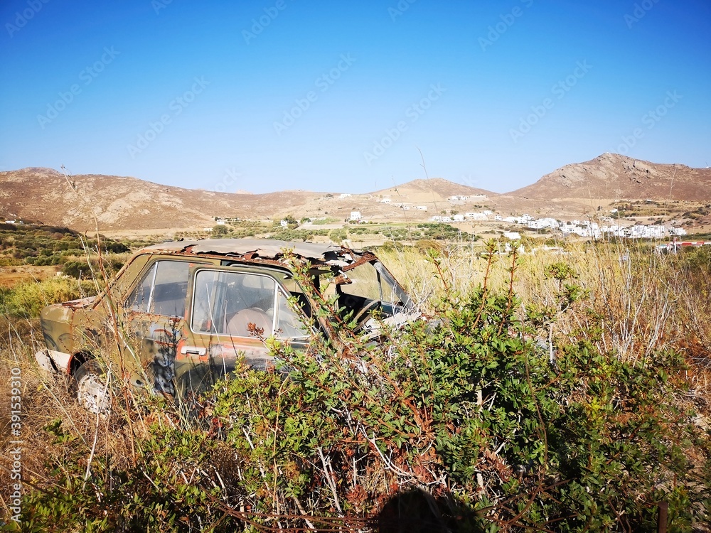 rusty old car before mountain and desert panorama opn the island of Naxos, Greece