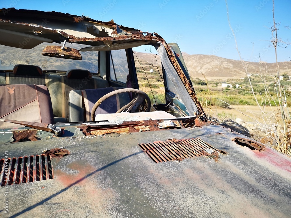 rusty old car before mountain and desert panorama opn the island of Naxos, Greece