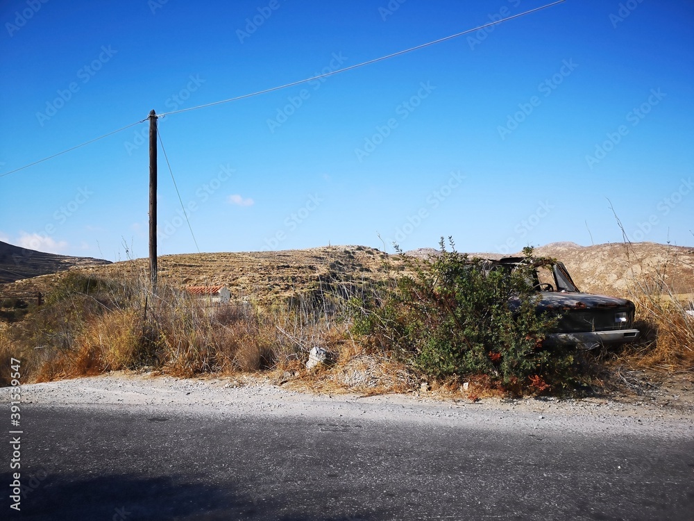 rusty old car before mountain and desert panorama opn the island of Naxos, Greece