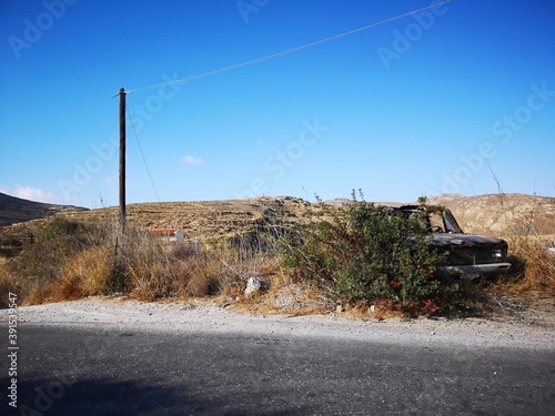 rusty old car before mountain and desert panorama opn the island of  Naxos, Greece photo