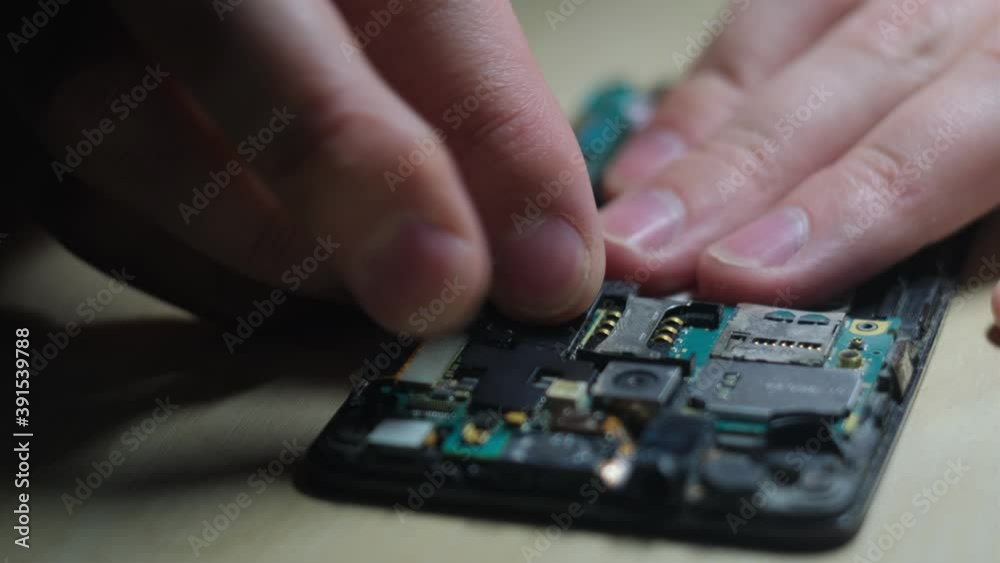 Master repairs a smartphone in a service center, closeup Master repairs a smartphone in a service center, closeup