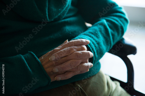 Detail of old wrinkly male hands praying, resting in wheelchair, 