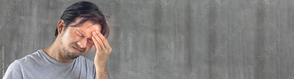 Portrait of young asian man suffering from severe headache against grey wall background with copy space, Man Having Strong Headache, Feeling Pain Portrait of young asian man suffering from severe headache against grey wall background with copy space, Man Having Strong Headache, Feeling Pain