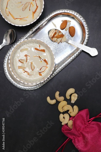 Milk Basundi is a popular Indian sweet. Also known as Rabdi or Rabri. Garnished with Dry fruits and Saffron. Served in a silver bowl over moody background. Copy space. Happy Diwali message. 