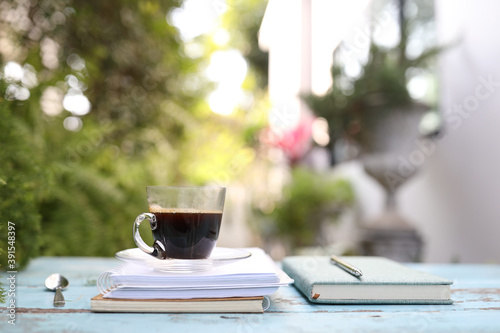 coffee in clear glass with spoon and notebook on blue wooden table 