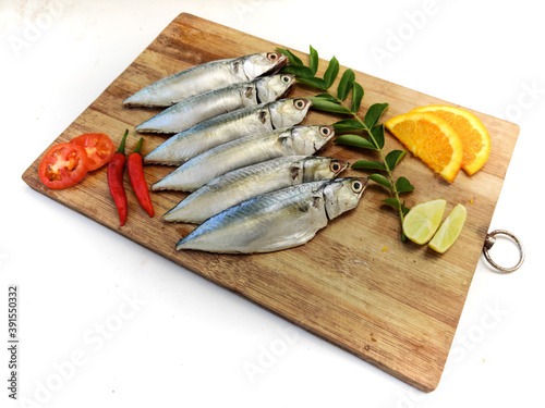 Cleaned and Ready to cook Fresh Fish Horse / Indian Mackerel Fish Decorated with herbs and Vegetables on a wooden pad. photo