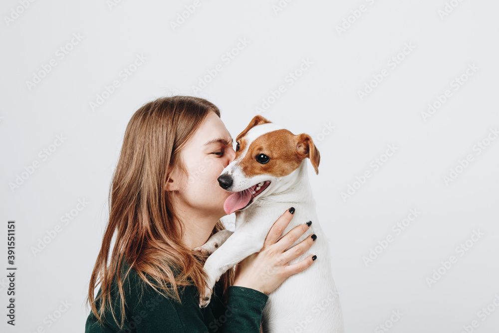 Cute young woman kisses and hugs her puppy jack russell terrier dog. Love between owner and dog. Isolated on white background. Studio portrait. Cute young woman kisses and hugs her puppy jack russell terrier dog. Love between owner and dog. Isolated on white background. Studio portrait.