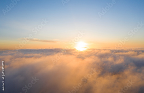 Aerial view gold sunrise over clouds in blue sky. Aerial top view cloudscape. Texture of clouds. View from above. Orange sunrise or sunset over clouds. Panorama clouds texture