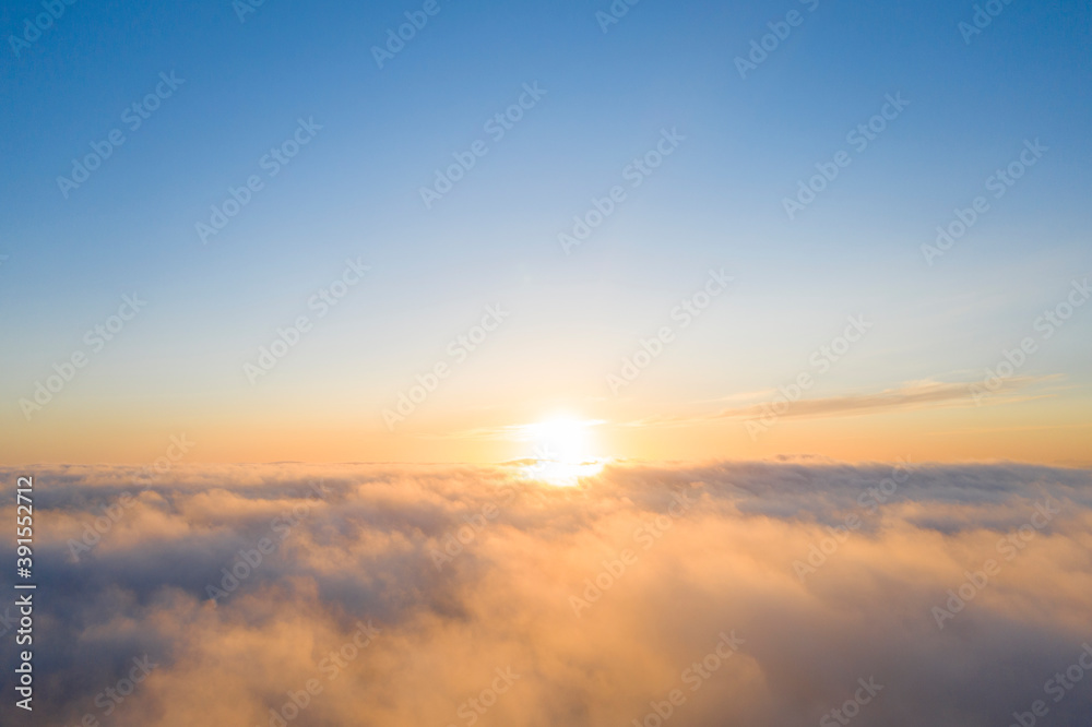 Aerial view gold sunrise over clouds in blue sky. Aerial top view cloudscape. Texture of clouds. View from above. Orange sunrise or sunset over clouds. Panorama clouds texture