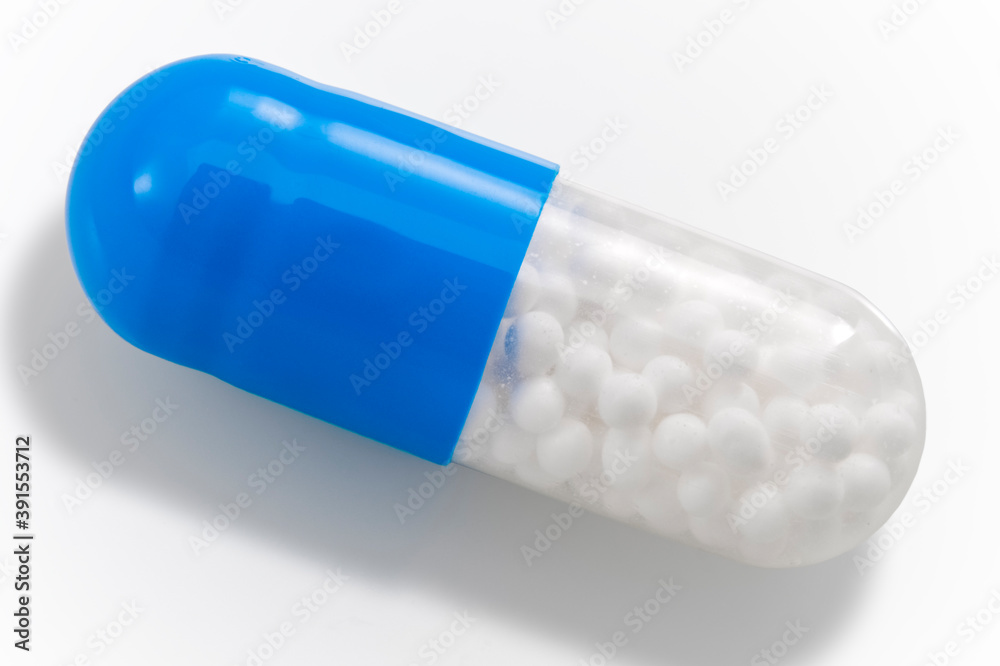 Pharmaceutical industry and pain management medication concept theme with close up on single blue and transparent pill filled with micro granules isolated on white background with clipping path cutout