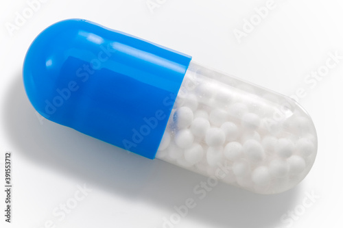 Obraz na płótnie Pharmaceutical industry and pain management medication concept theme with close up on single blue and transparent pill filled with micro granules isolated on white background with clipping path cutout w salonie