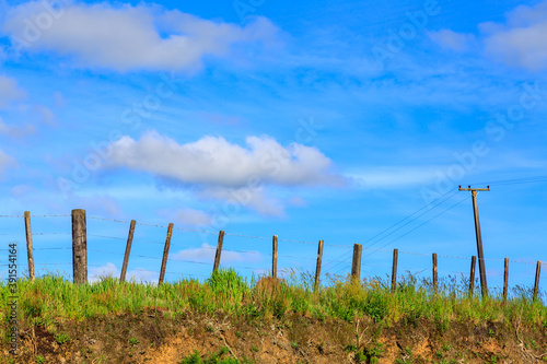 A wire fence on a farm, with a bright blue sky in the background. Photographed in New Zealand