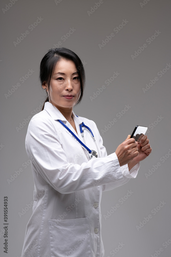 Concerned female Asian doctor holding a mobile Concerned female Asian doctor holding a mobile