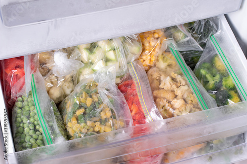 Plastic bags with deep frozen vegetables in refrigerator, closeup