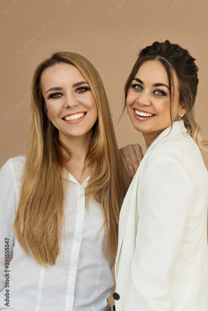 Portrait two laughing young women on a beige background Portrait two laughing young women on a beige background
