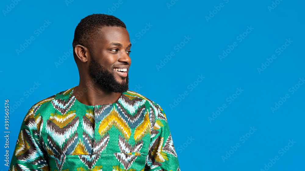 Positive black man in african shirt looking at copy space Positive black man in african shirt looking at copy space