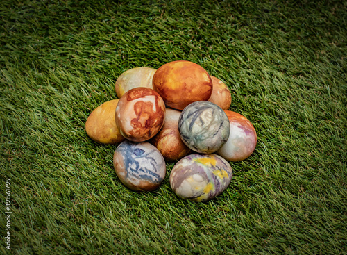 A pile of Easter eggs, colored traditionally with onion peels and yarn, in spring grass with copy space around them