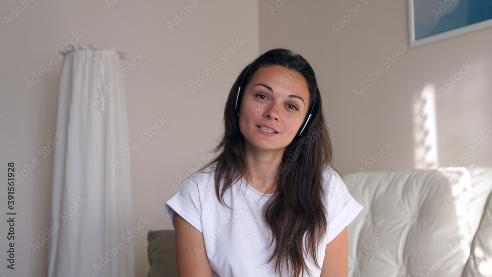 Young business woman wears headset talks to web camera making distance online video conference call. Female internet teacher doing distant chat working from home. Webcam view Young business woman wears headset talks to web camera making distance online video conference call. Female internet teacher doing distant chat working from home. Webcam view