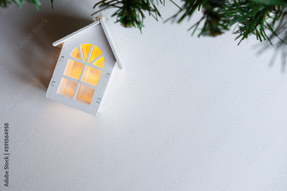 glowing wooden house garland on a Christmas tree on a white background. New year and christmas concept, real estate concept.