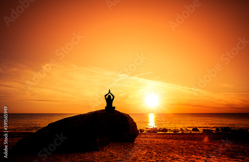 Frau bei sonnenuntergang am Strand in Yoga Pose
