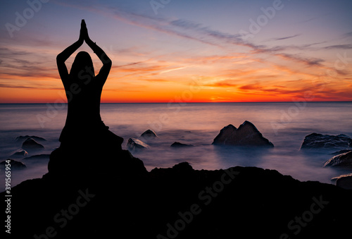 Frau bei sonnenuntergang am Strand in Yoga Pose