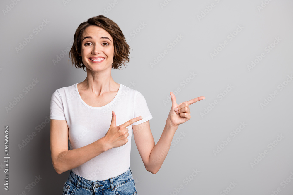 Photo of young attractive girl happy positive smile wear denim point fingers recommend advise isolated over grey color background Photo of young attractive girl happy positive smile wear denim point fingers recommend advise isolated over grey color background