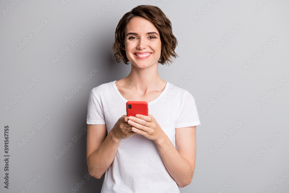 Photo of young attractive girl happy smile hold cellphone mobile chat type isolated over grey color background - obrazy, fototapety, plakaty 
