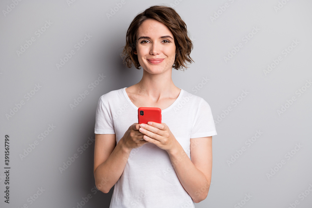 Photo of young cheerful smile blogger girl hold smartphone chat type browse isolated over grey color background - obrazy, fototapety, plakaty 