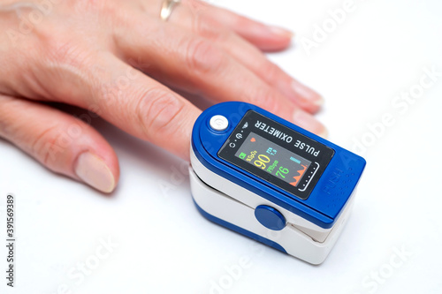 Close up of Finger in an Oximeter Device. Pulse oximeter on white background. photo