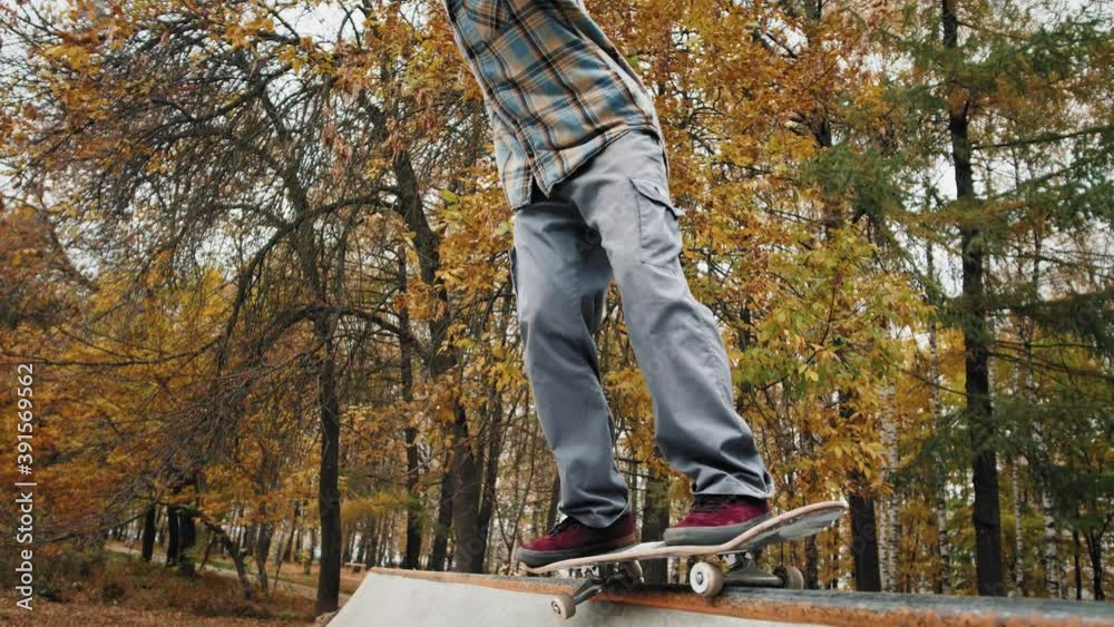 Skater practicing in the autumn concrete skate park, making tricks and rides in ramp. Skateboarder making tricks, manual balance, boardslide and stalls, professional extreme sport Skater practicing in the autumn concrete skate park, making tricks and rides in ramp. Skateboarder making tricks, manual balance, boardslide and stalls, professional extreme sport