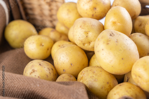 New raw potatoes in a wicker basket on a brown background close up