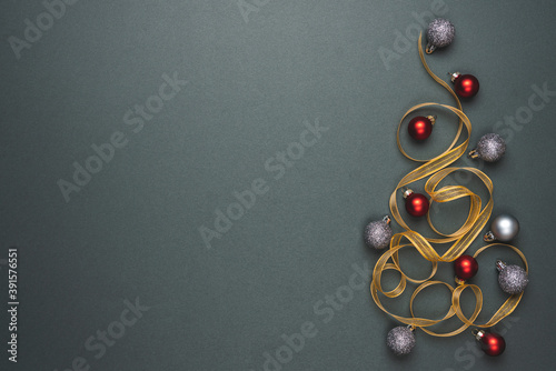 Christmas tree made of shiny gold ribbons with sparkling decorations. Dark grey background. Christmas tree as symbol of Happy New Year, Merry Christmas holiday celebration