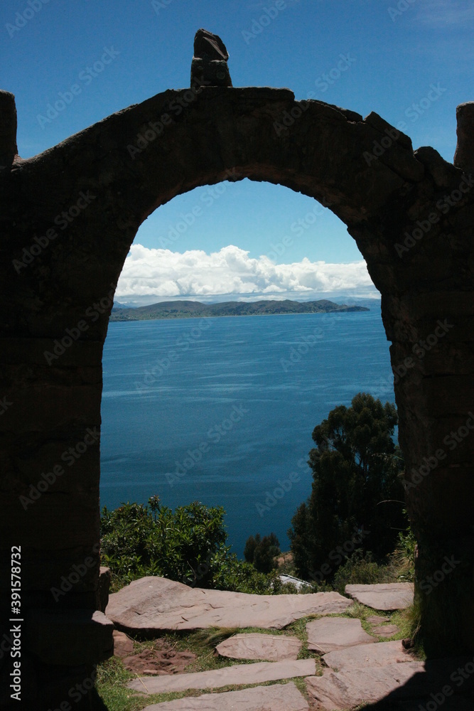 View over the ocean through a stone gate covered in shadows