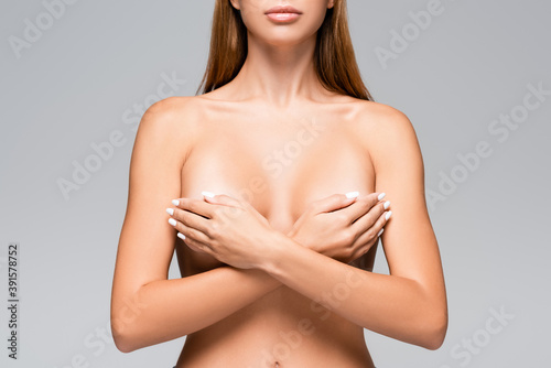 Cropped view of nude woman covering breast with hands isolated on grey