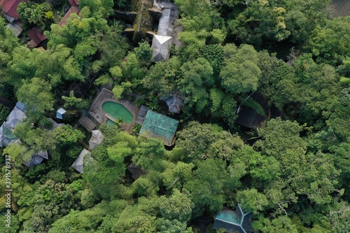 Aerial view of a tropical lodge showing the swimming pool surrounded by the lush green canopy of a tropical rainforest
