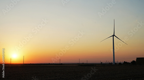 Sunset with clear sky behind wind power plant, which produce green energy, ecology concept