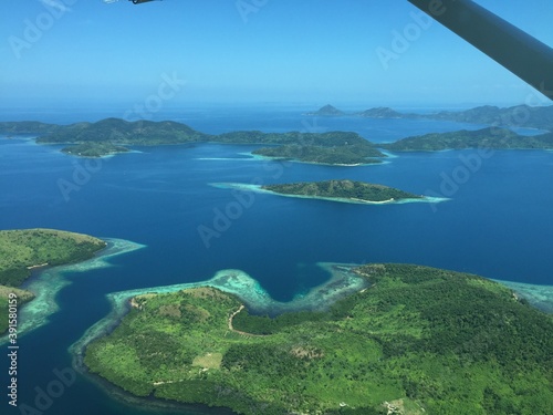 View from a small aircraft over the many islands surrounded by tropical reefs and covered in forest at the coast of thailand