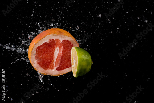 citrus fruits in water splash on black background