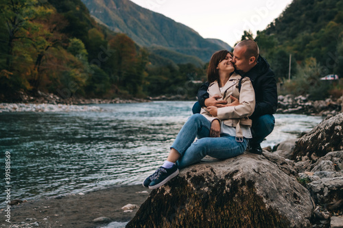 Young couple kissing and hugging near the lake in the mountains.