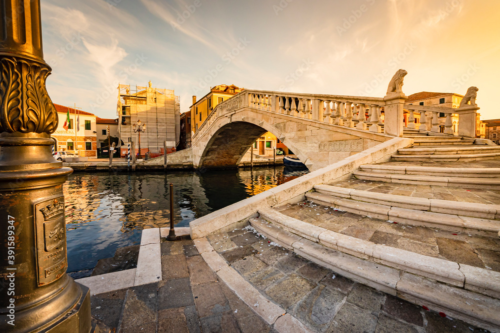 Naklejka premium Romantic cityscape of Ghioggia - near Venice - with canals, buidings, bridges and canals in sunset sunlight. Bridge di Vico