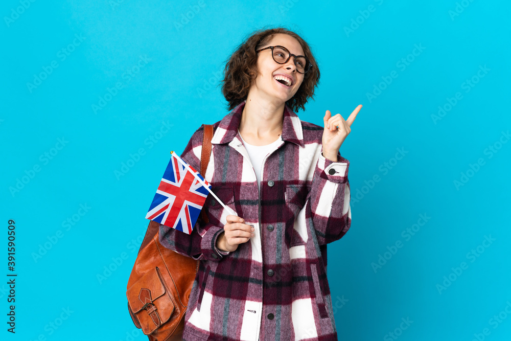 Young English woman holding an United Kingdom flag isolated on blue background pointing up a great idea Young English woman holding an United Kingdom flag isolated on blue background pointing up a great idea