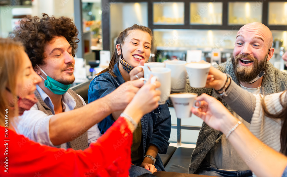 Friends drinking coffee inside a bar restaurant. New normal friendship with happy group having fun together wearing protective face mask. students toasting fancy cappuccino at cafe. millennials people