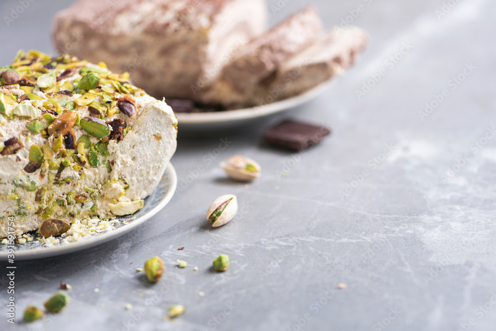 Sesame chocolate halva and halva with pistachios on grey background