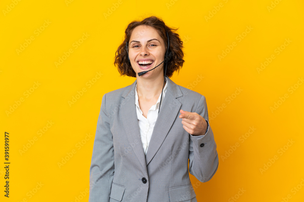 Young English woman isolated on yellow background surprised and pointing front