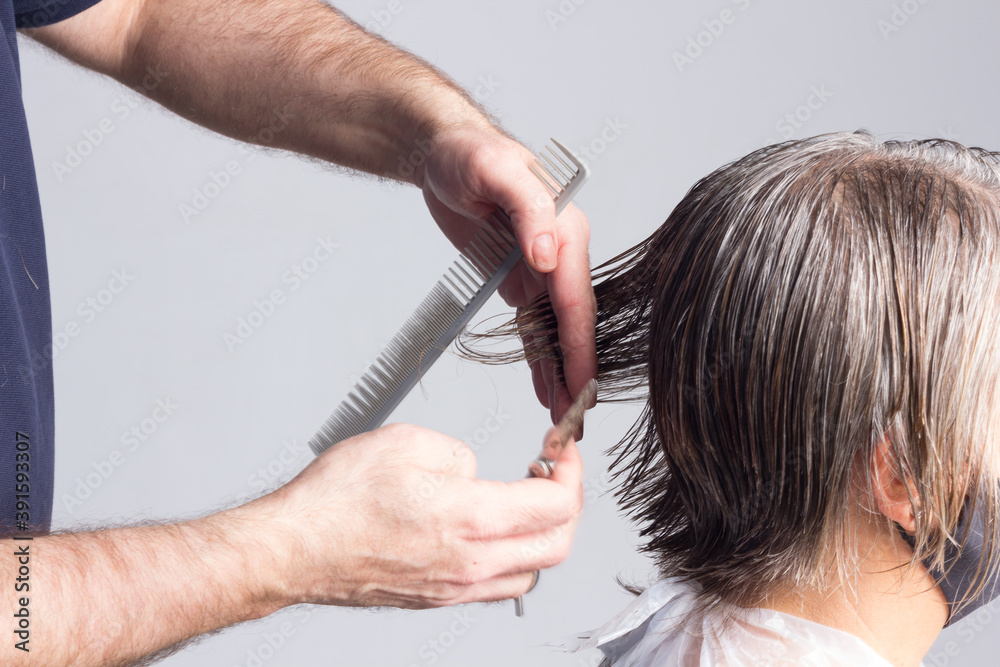 Fototapeta premium Hairdresser trimming brown hair with scissors