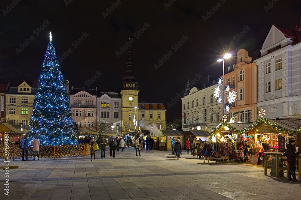 Ostrava, Czech Republic. Christmas market on Masaryk square with city's main Christmas tree in dusk. The Old Town Hall is located at the opposite end of the square.