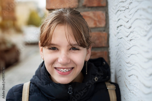 The young girl stopped to rest after a long walk around the city with her friends, the girl is smiling, clearly seen braces on her teeth