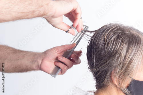 Hairdresser trimming brown hair with scissors